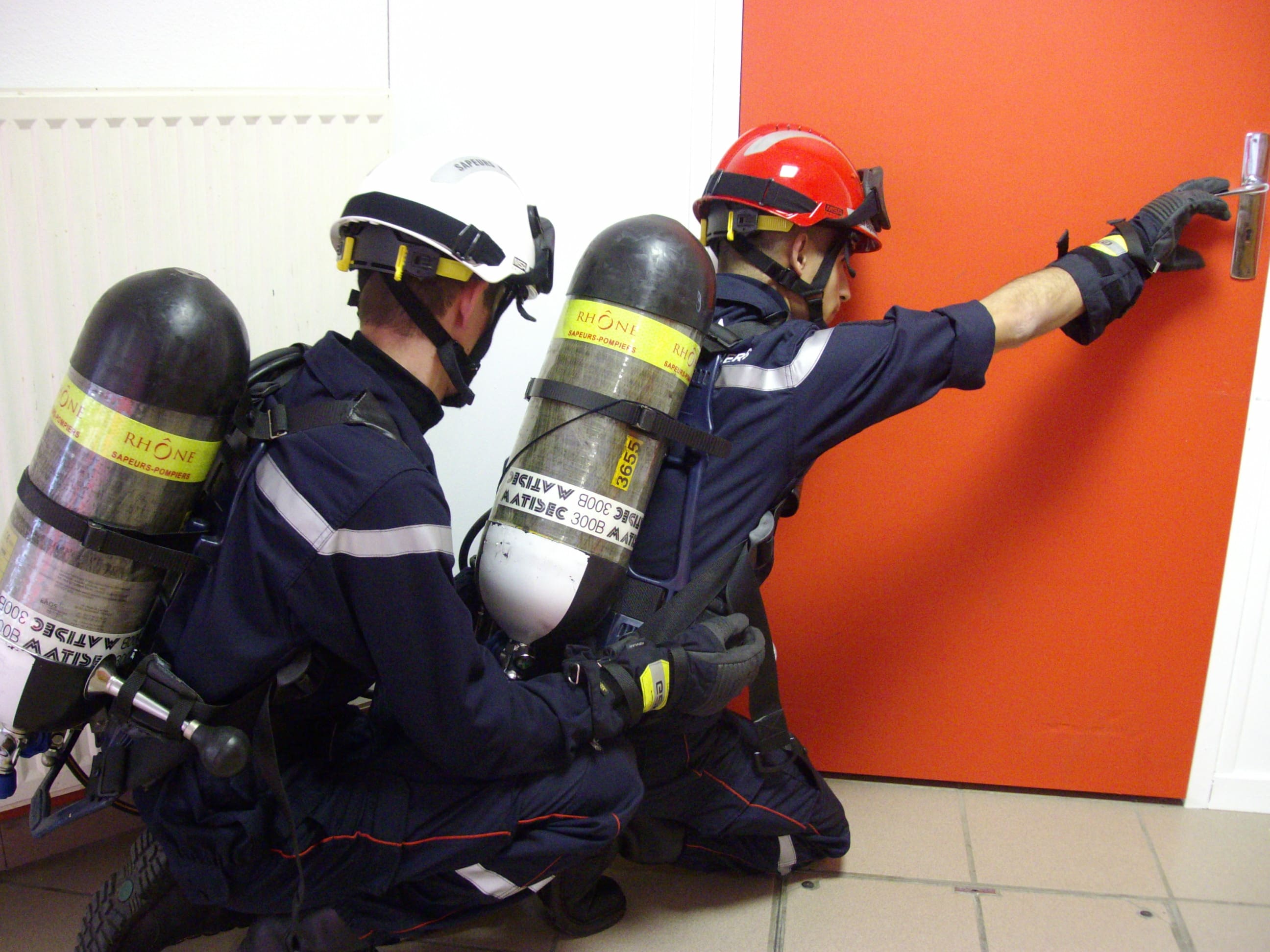 Deux pompiers avec appareils respiratoires près d'une porte