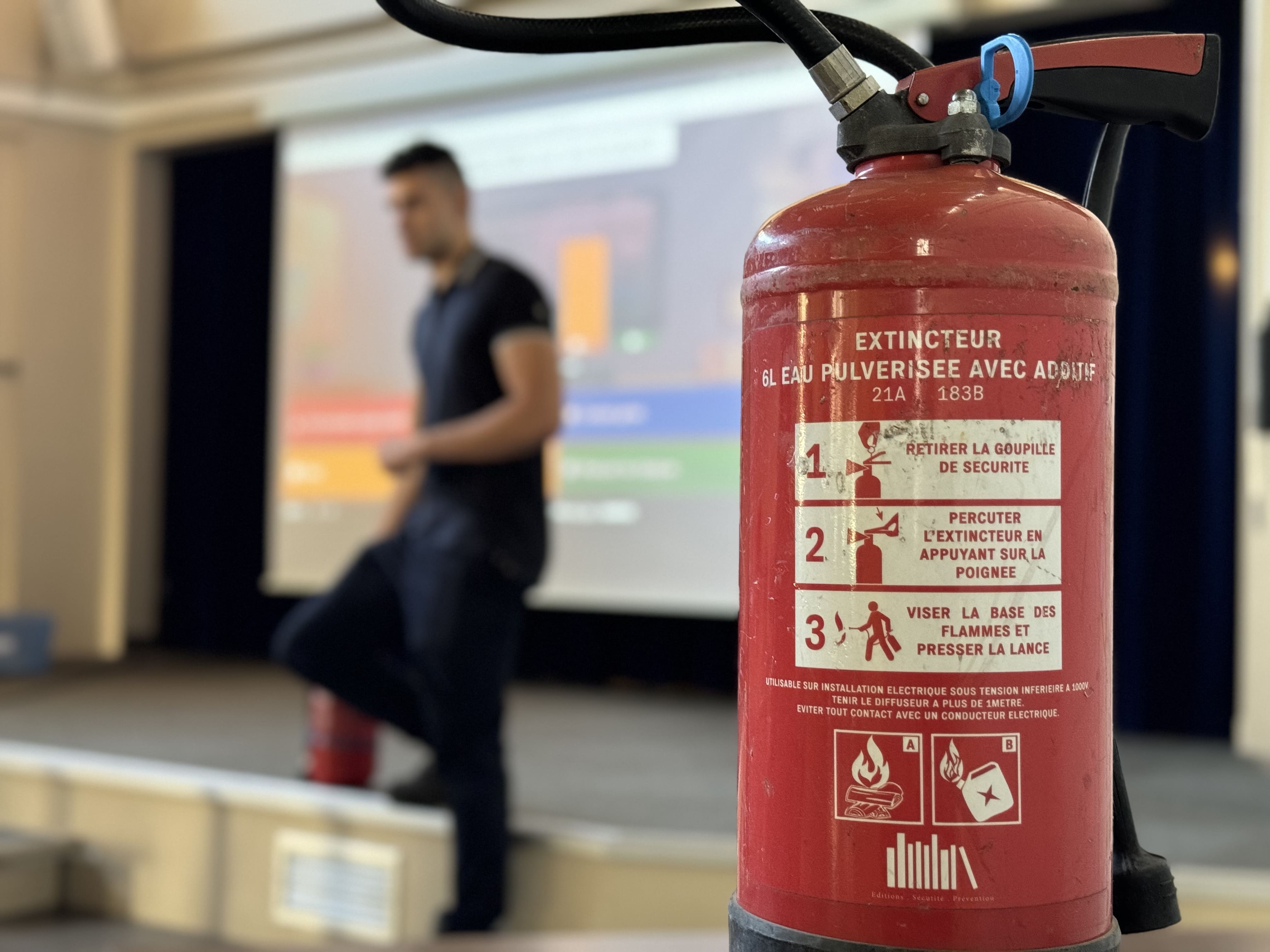 Extincteur en premier plan lors d'une formation incendie